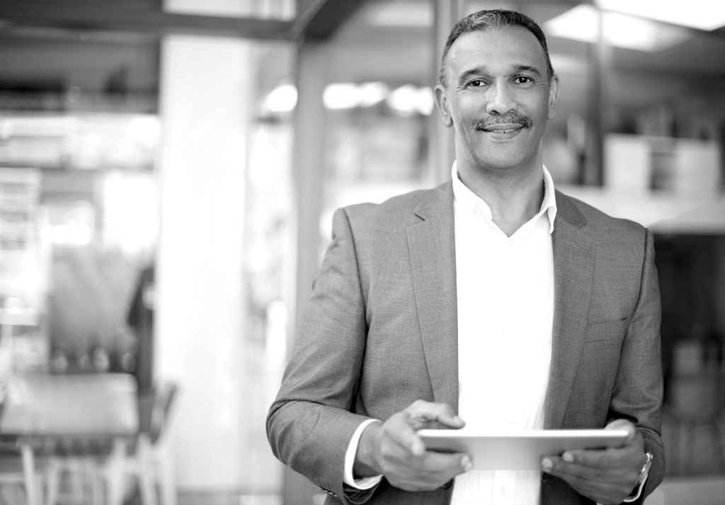 A financial advisor standing in an office holding a digital tablet